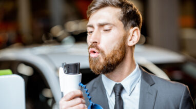 Man blowing on electric car charger like it's a pistol - car insurance in Washington