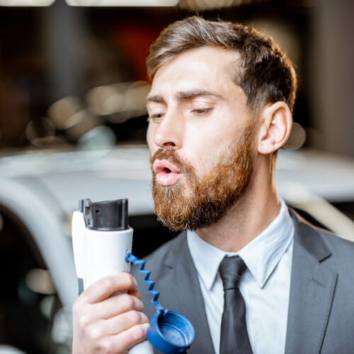 Man blowing on electric car charger like it's a pistol - car insurance in Washington