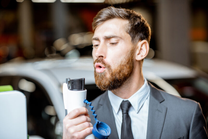 Man blowing on electric car charger like it's a pistol - car insurance in Washington