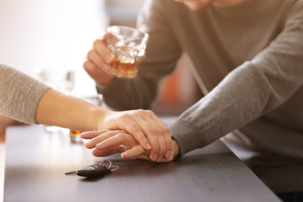 A woman's hand stops a man's hand from grabbing the car keys when he has a drink in his other hand - cheap DUI insurance in Washington