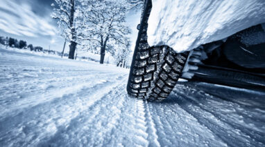 Close up of tire driving on snowy winter road.