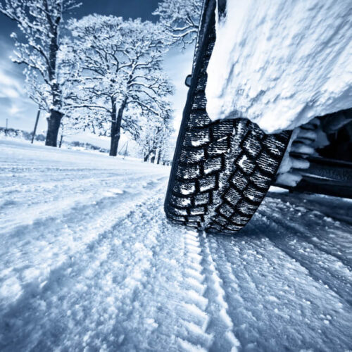 Close up of tire driving on snowy winter road.