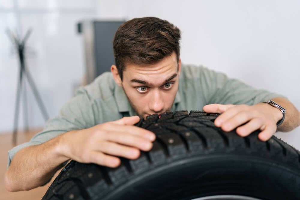 Funny picture of man staring intently at his tire.