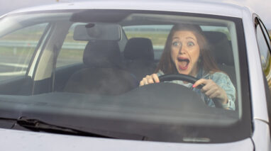 A girl screaming behind the wheel.
