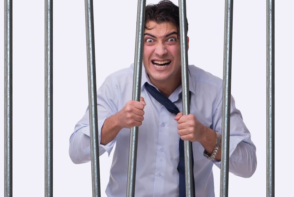 Funny man behind bars, bending the bars and grimacing at the camera, cheap car insurance in Washington.