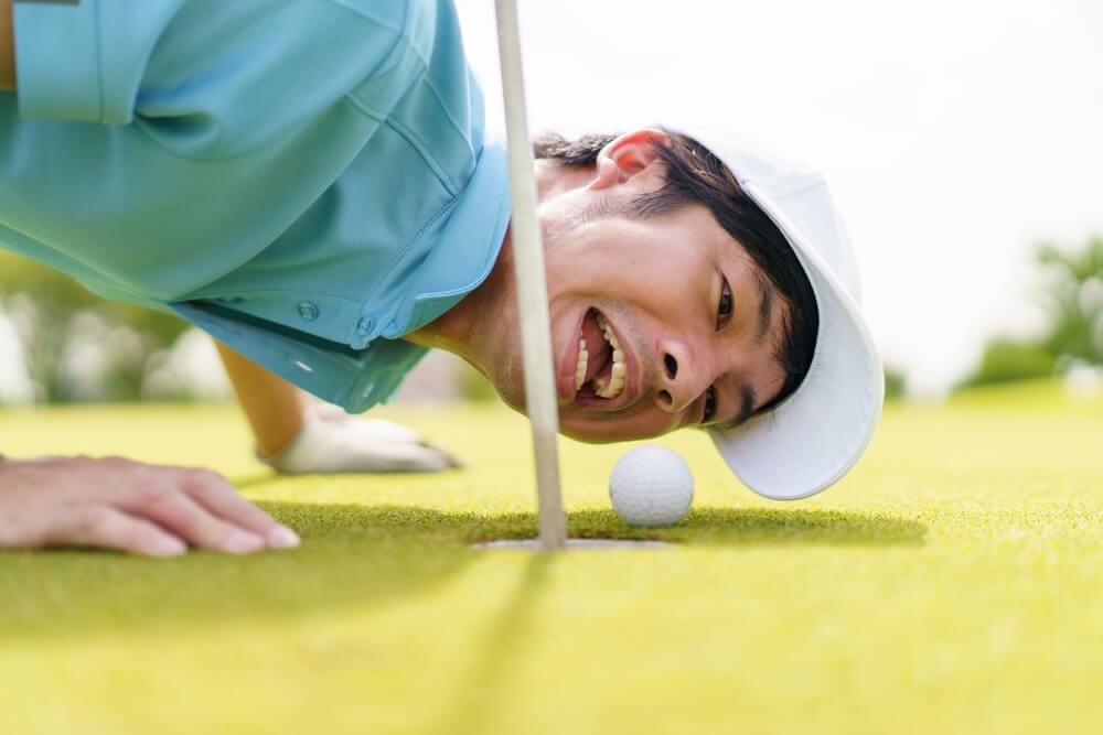 Golfer lining up a close putt, highlighting the oddest things ever covered by insurance for sports mishaps.