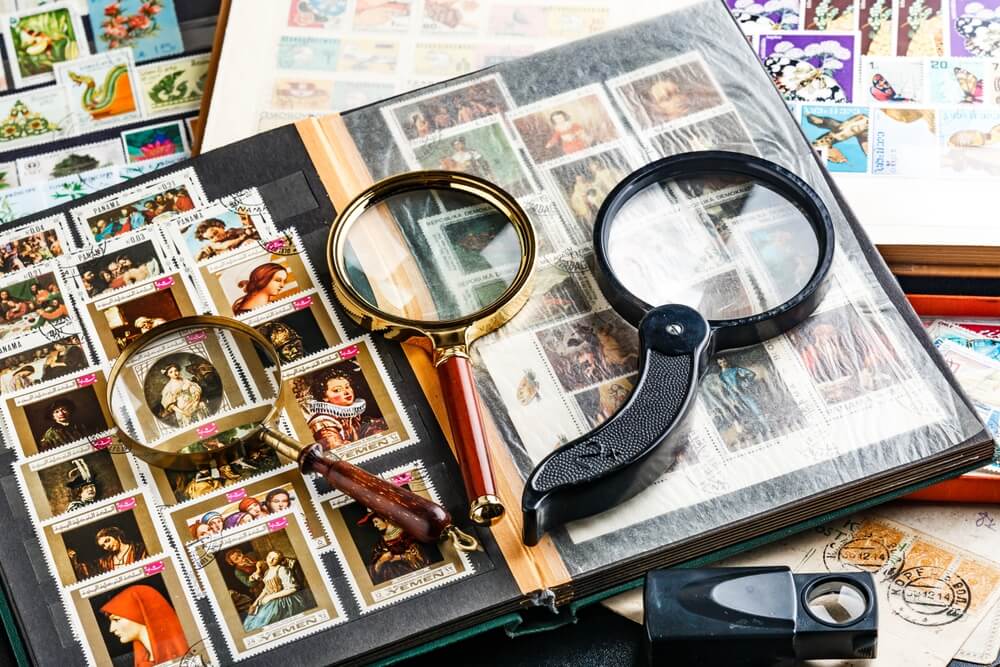 Stamp collection under magnifying glasses, representing the oddest things ever covered by insurance for valuable collectibles.