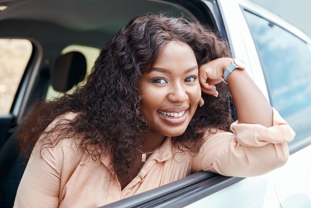 Smiling driver leaning out of her car while learning about SR-22 insurance in Washington State.