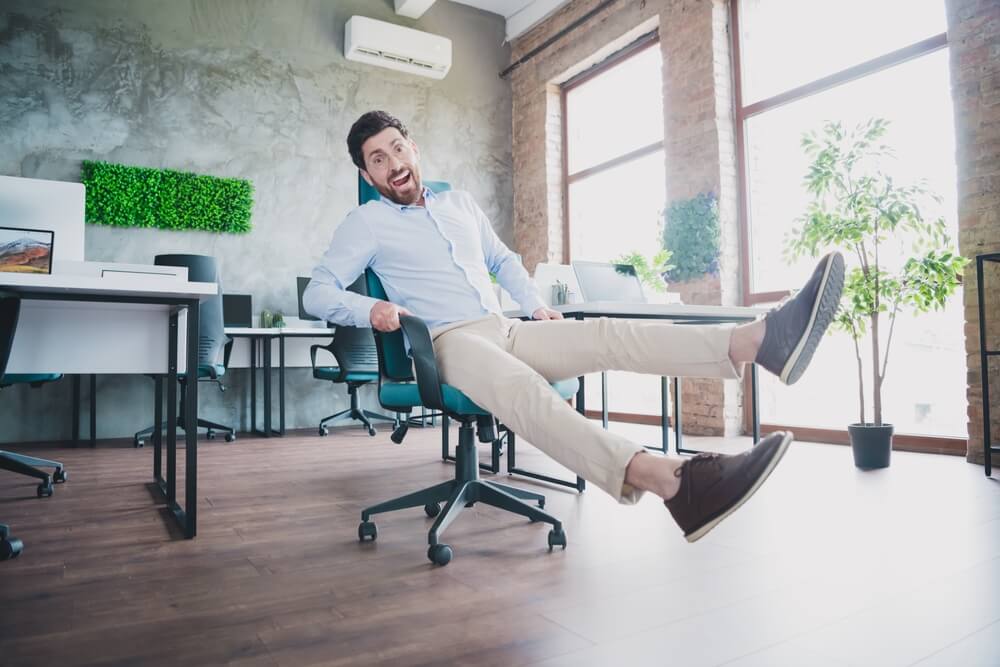 Man rides his office chair as it slides along an uneven floor - cheap home insurance in Seattle.