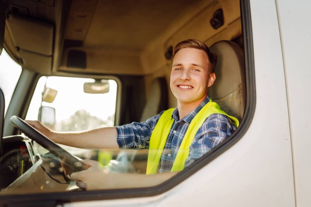 Smiling truck driver looks out the window of his truck - cheap commercial auto insurance in Washington.