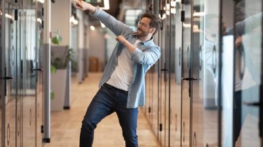 Happy business man dances in the halls because his company is protected with cheap business insurance in Washington.