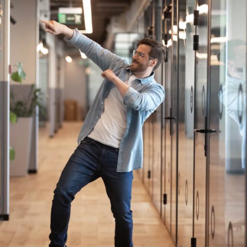 Happy business man dances in the halls because his company is protected with cheap business insurance in Washington.