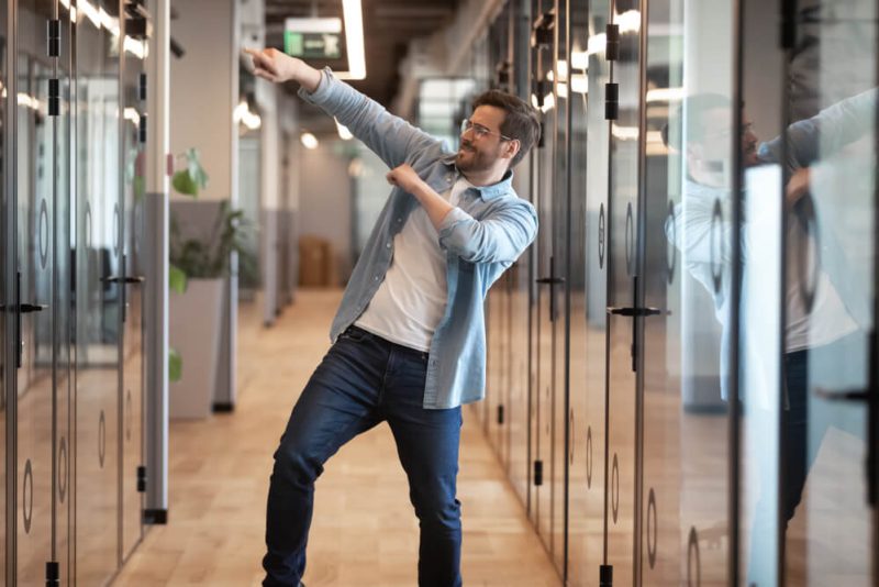 Happy business man dances in the halls because his company is protected with cheap business insurance in Washington.