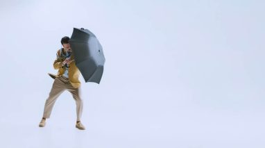 Bad weather. Portrait of young businessman fighting the wind with umbrella isolated on white background. Concept of rain and how to protect your business with the right insurance in Washington.