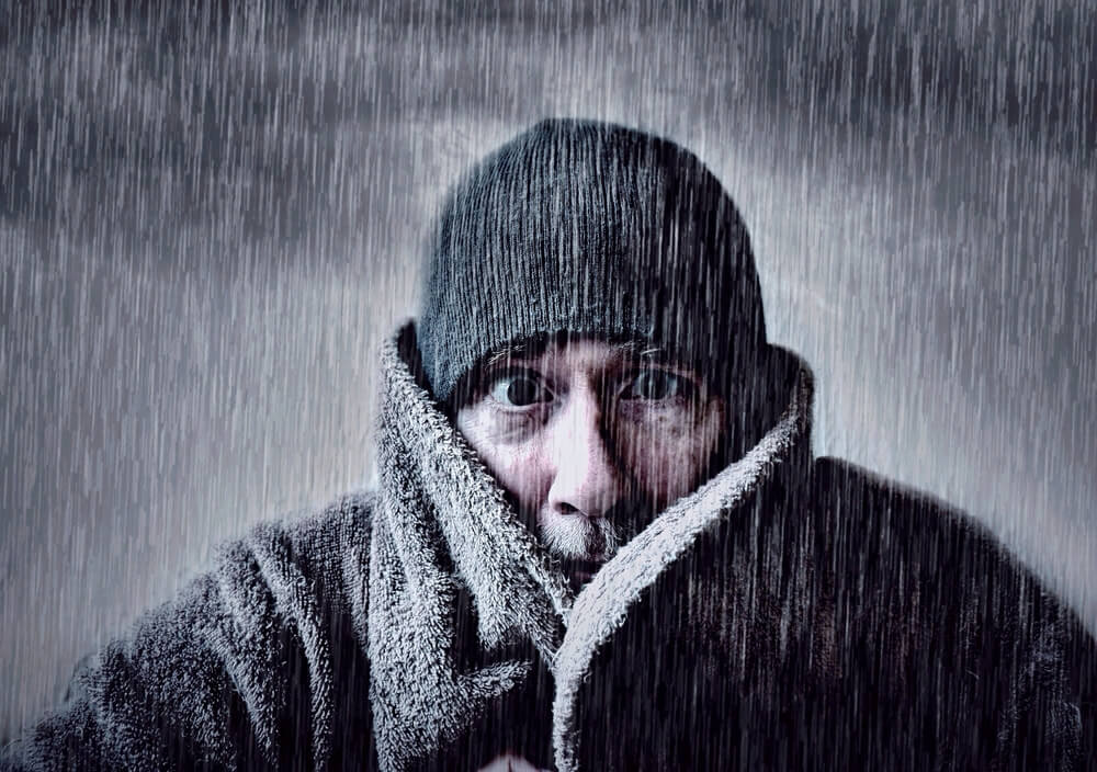 Man shivering in torrential rain, business insurance for when it rains on your company.