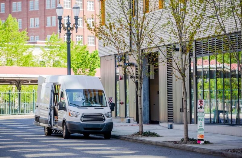 Compact commercial transportation economical, convenient minivan for small business or local moving and delivery of goods loading cargo from multilevel building in the city downtown.