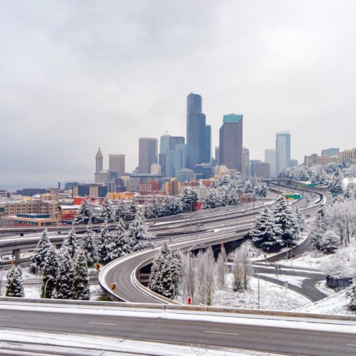 Downtown Seattle is covered in snow on a cloudy winter day, highlighting how harsh weather makes commercial auto insurance essential for businesses on the road