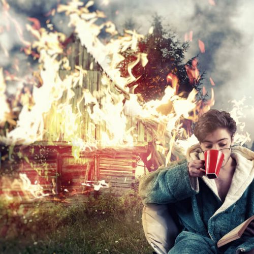 Man drinks coffee and reads a book while his house burns in the background, symbolizing insurance mistakes Washington.