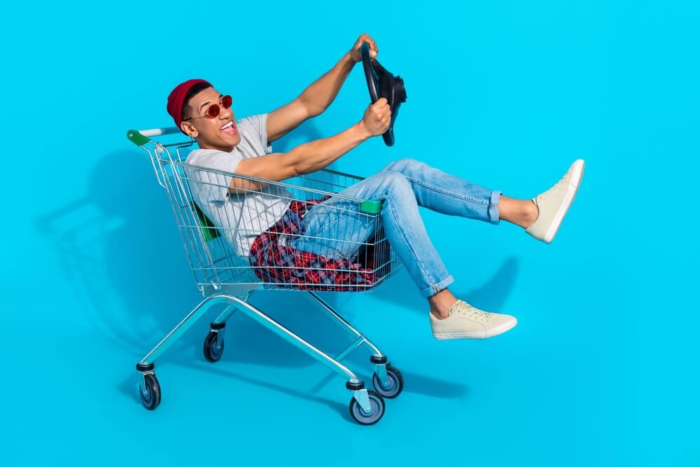 Person playfully riding in a shopping cart, symbolizing risky behavior that can lead to unexpected car insurance claims.