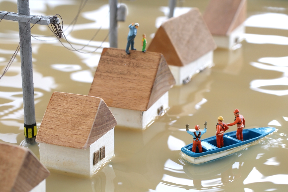 Miniature houses flooded with rescue workers assisting residents, symbolizing risks from extreme weather and the importance of home insurance winter protection
