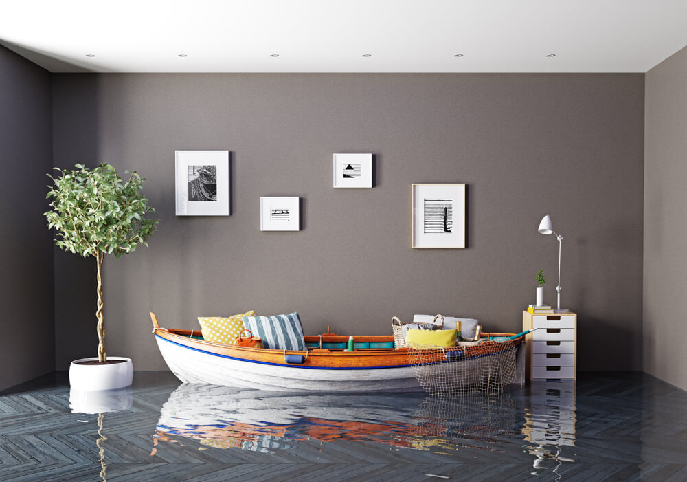 Flooded living room with water covering the floor and a small boat used as a couch beside a lamp and framed wall art, highlighting home insurance myths.