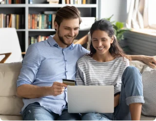 Man and woman looking at laptop and with credit card in hand